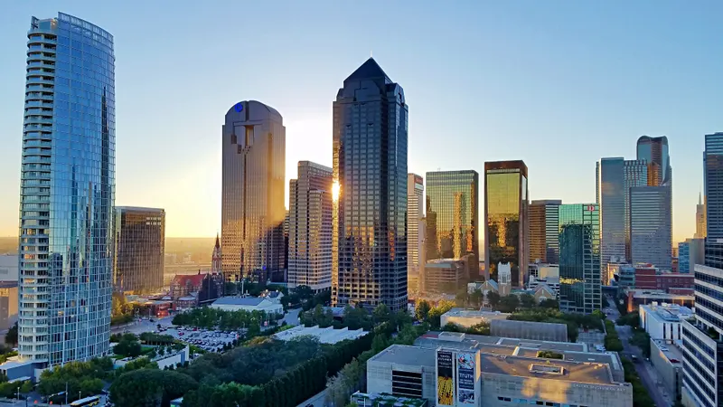 Downtown Dallas skyscrapers lit by low morning sun above the tree-lined Arts District